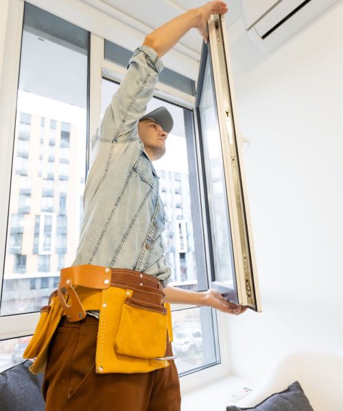 Construction worker installing window in house.