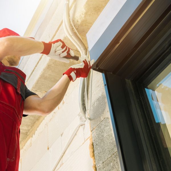 Electric Exterior Window Roller Shutters Installation Performed by Professional Caucasian Shutters Technician.