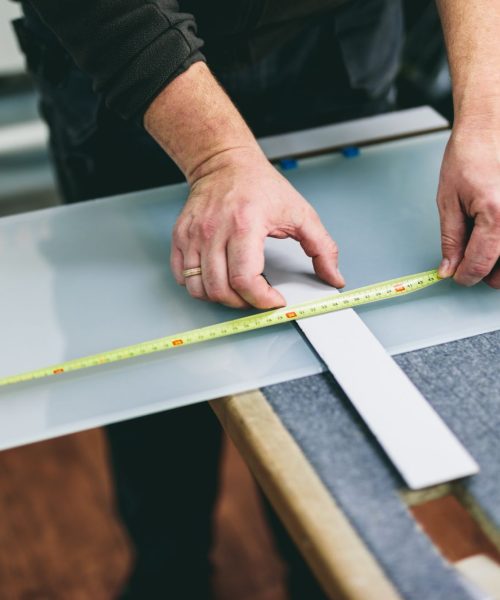 Glazier worker measuring glass in workshop. Industry and manufactory production