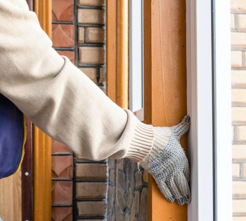 gluing protective decorative corner to frame of plastic window on veranda of country house